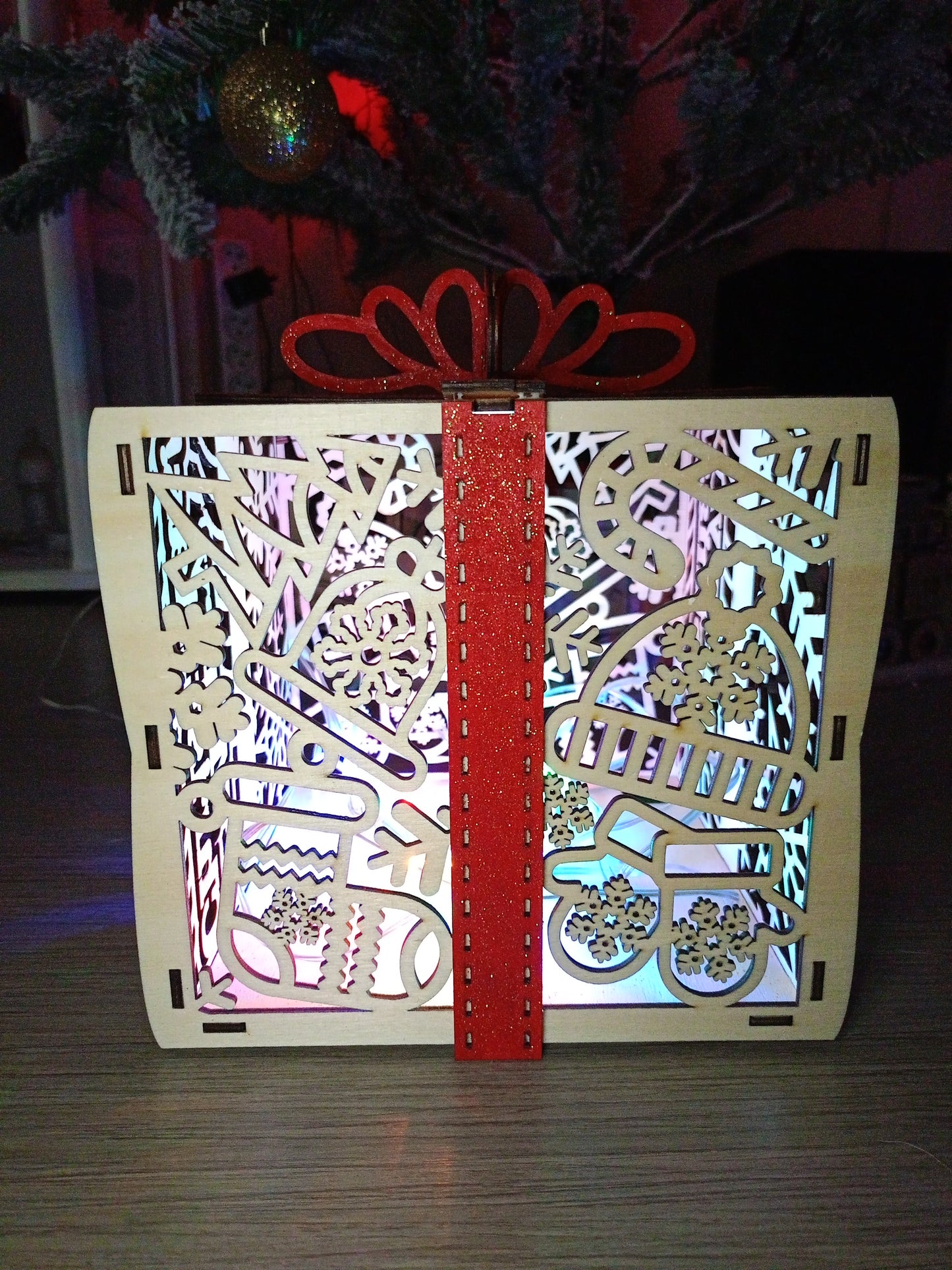 Lanterne de Noël en bois sculpté – Éclairage LED multicolore et ruban rouge pailleté 🎁